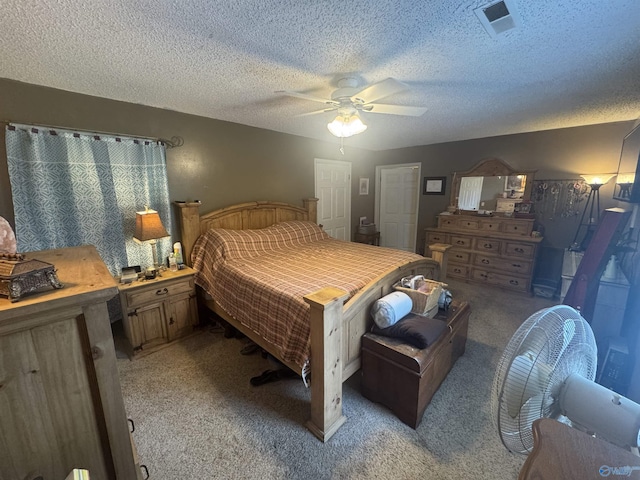 bedroom with a ceiling fan, light carpet, visible vents, and a textured ceiling