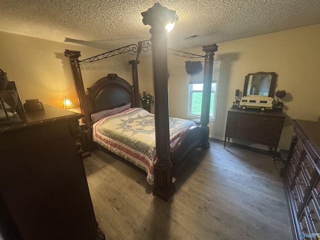 bedroom with a textured ceiling, visible vents, and wood finished floors