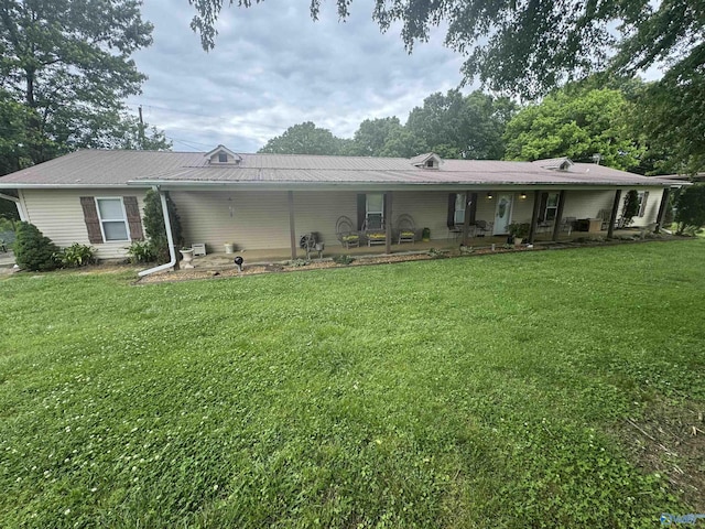 rear view of house featuring covered porch and a lawn