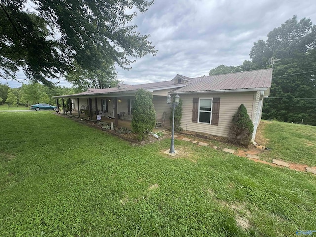 view of front of home with metal roof, a patio area, and a front lawn