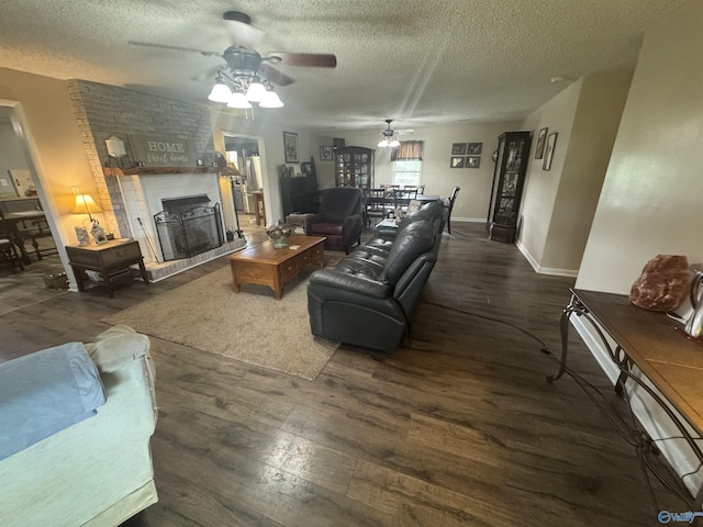 living room featuring wood finished floors, a textured ceiling, a fireplace, a ceiling fan, and baseboards