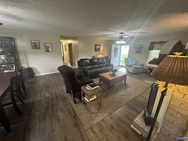 living area featuring a textured ceiling, wood finished floors, baseboards, and ceiling fan