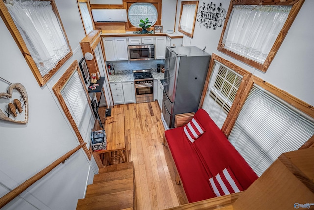 kitchen with decorative backsplash, appliances with stainless steel finishes, light hardwood / wood-style floors, and white cabinetry