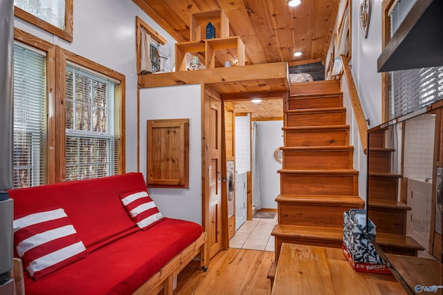 interior space with a towering ceiling, light hardwood / wood-style floors, and wooden ceiling