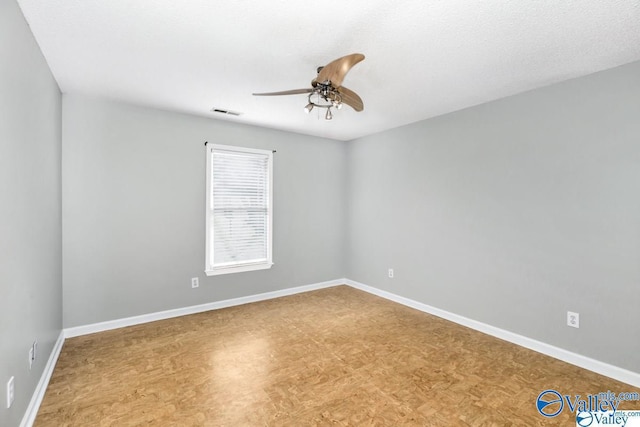 unfurnished room featuring ceiling fan, visible vents, and baseboards