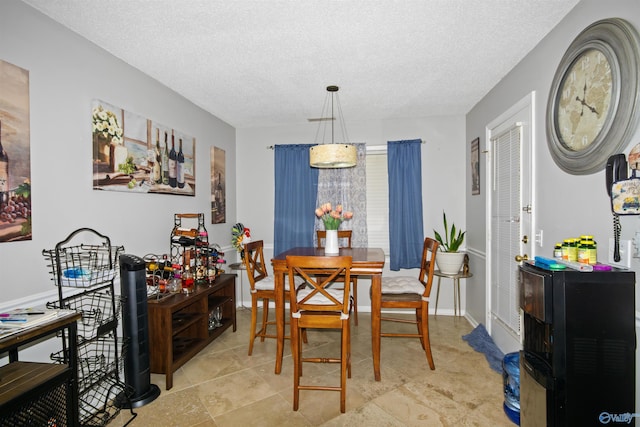 dining room with a textured ceiling and baseboards