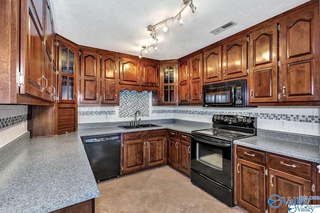 kitchen with a textured ceiling, a sink, visible vents, black appliances, and glass insert cabinets