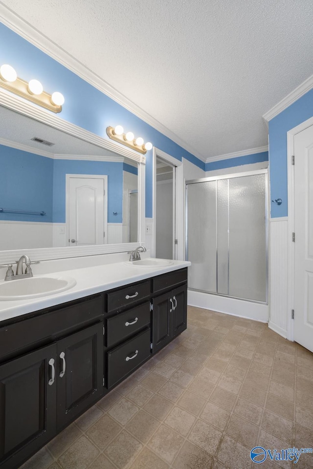 bathroom with vanity, a textured ceiling, a shower with door, and ornamental molding