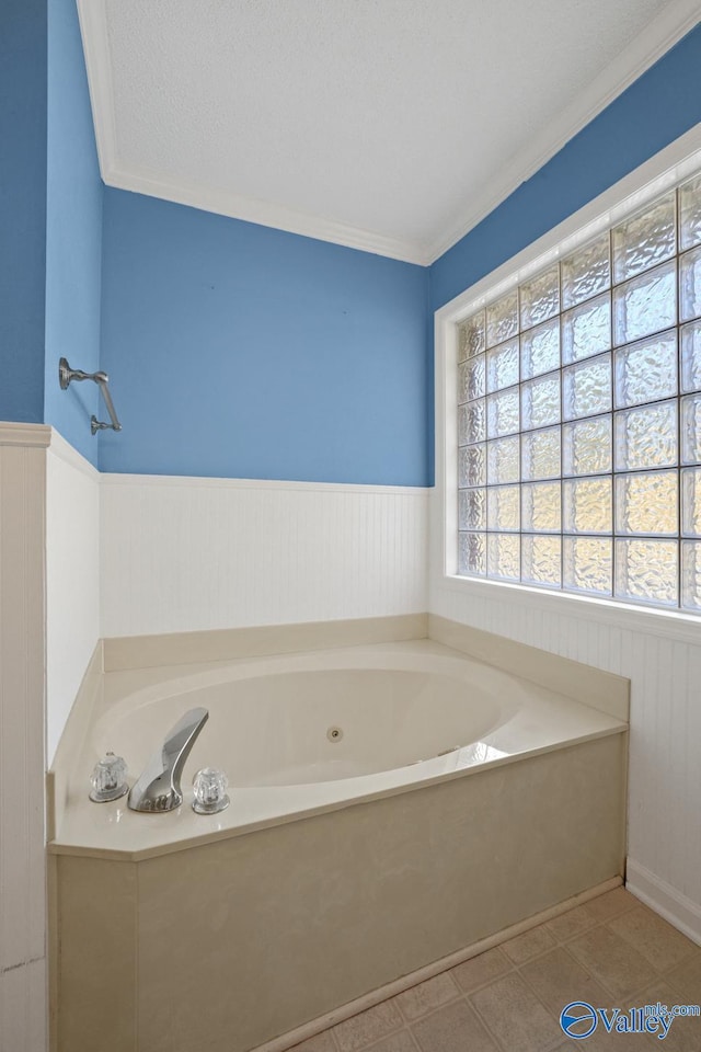 bathroom with a textured ceiling, tile patterned flooring, a tub to relax in, and crown molding