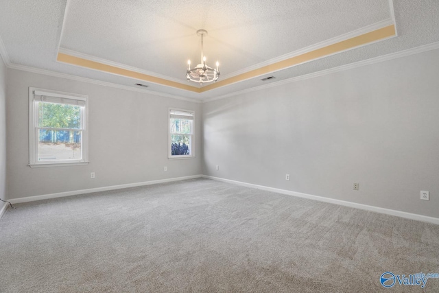 unfurnished room with an inviting chandelier, ornamental molding, carpet floors, and a tray ceiling