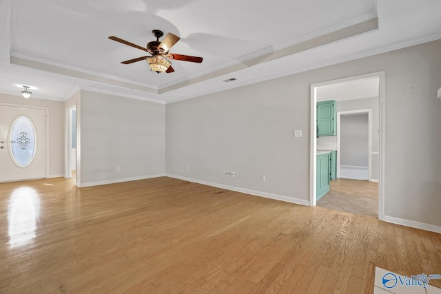 unfurnished living room with light hardwood / wood-style floors, ceiling fan, crown molding, and a tray ceiling