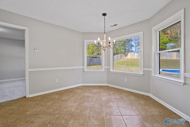 tiled spare room featuring a textured ceiling and a chandelier