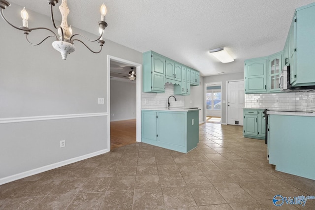 kitchen with backsplash, ceiling fan with notable chandelier, a textured ceiling, dark tile patterned floors, and decorative light fixtures