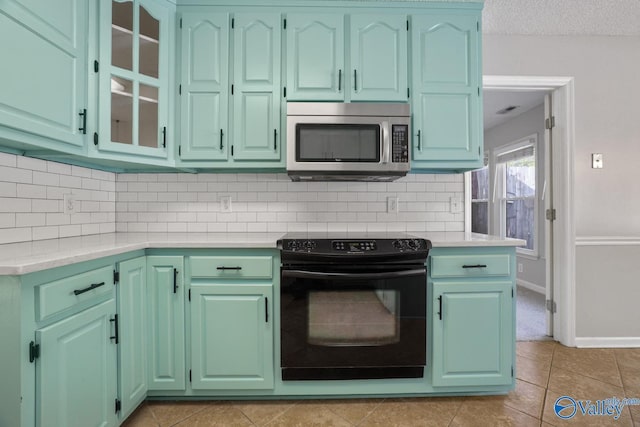 kitchen featuring decorative backsplash, electric range, light tile patterned floors, and a textured ceiling