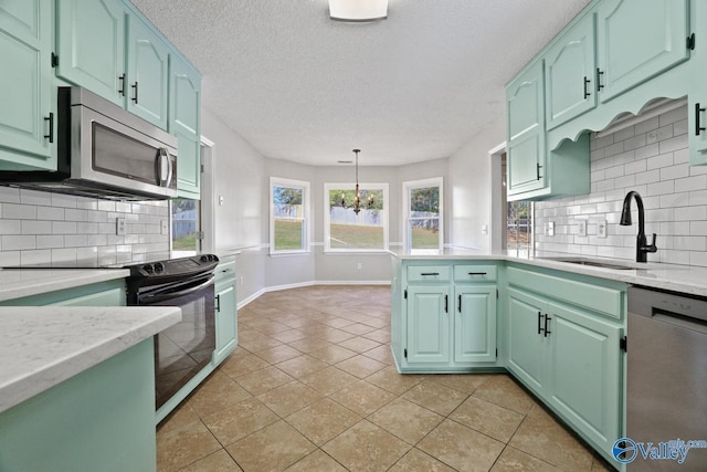 kitchen with sink, an inviting chandelier, tasteful backsplash, pendant lighting, and appliances with stainless steel finishes