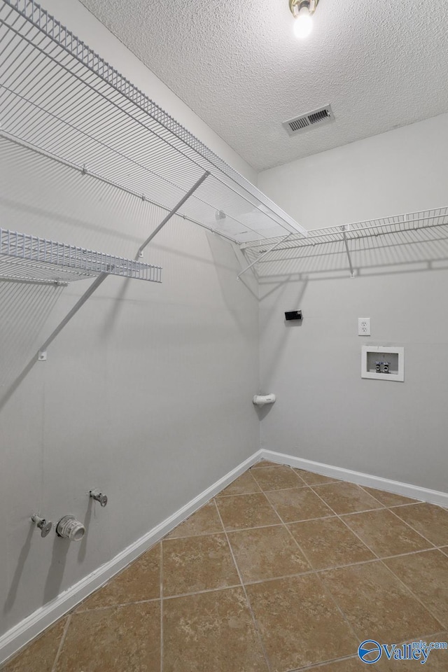 laundry area featuring tile patterned floors, washer hookup, and a textured ceiling