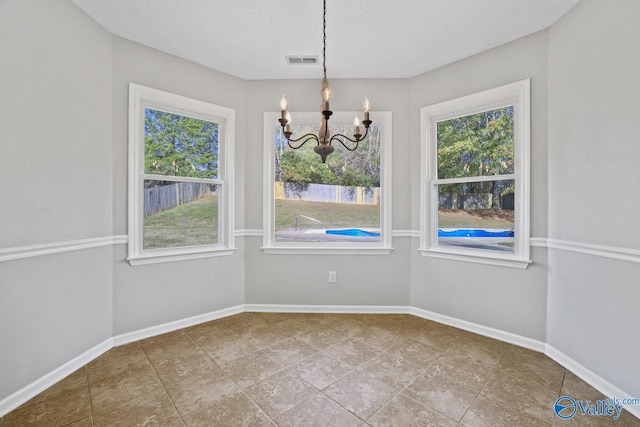 unfurnished dining area with a textured ceiling and a chandelier