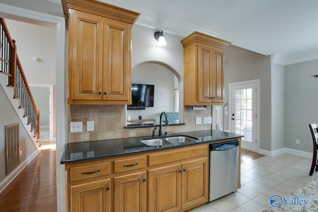 kitchen featuring dark stone counters, dishwasher, light tile patterned flooring, sink, and decorative backsplash