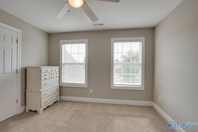 unfurnished bedroom featuring ceiling fan, light carpet, and multiple windows