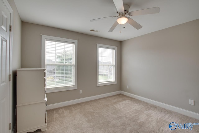 unfurnished room with ceiling fan, light colored carpet, and a wealth of natural light