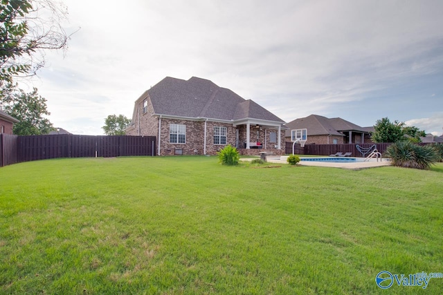 back of property with a fenced in pool, a lawn, and a patio area