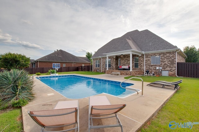 view of pool with ceiling fan, a lawn, and a patio