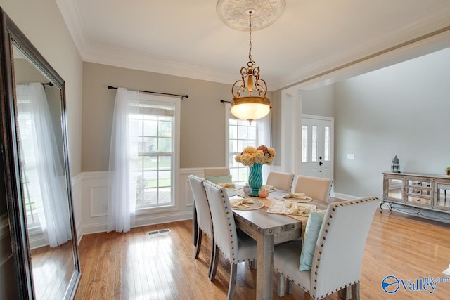 dining area with light hardwood / wood-style flooring and ornamental molding