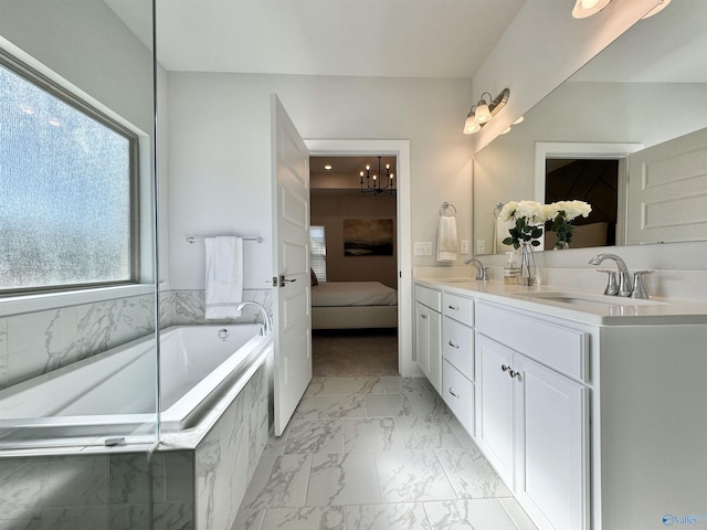 bathroom featuring tiled bath, vanity, and an inviting chandelier