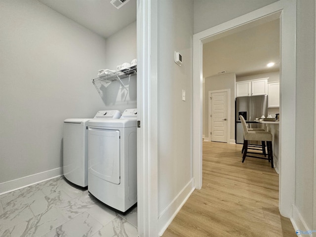 washroom with light hardwood / wood-style floors and washer and clothes dryer