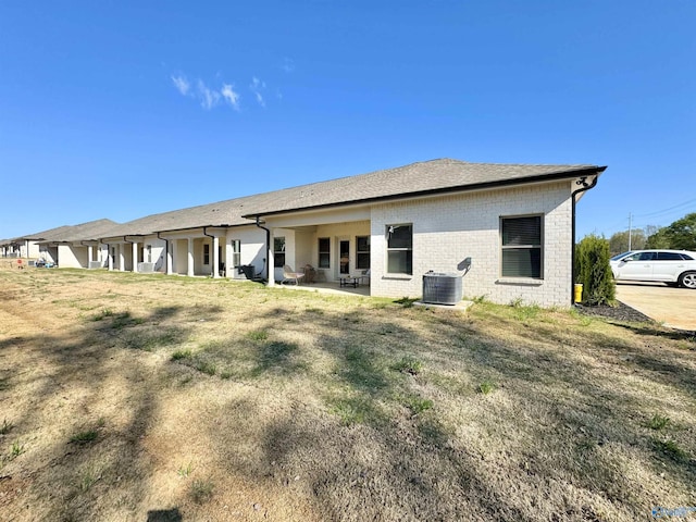 rear view of house featuring central AC and a yard