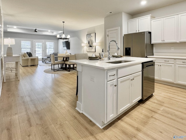 kitchen featuring white cabinets, appliances with stainless steel finishes, a center island with sink, and ceiling fan