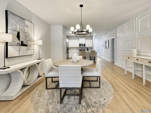 dining space with light wood-type flooring and an inviting chandelier