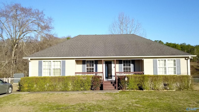 single story home featuring covered porch, a shingled roof, and a front lawn