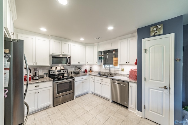kitchen featuring light stone countertops, appliances with stainless steel finishes, a sink, white cabinetry, and visible vents
