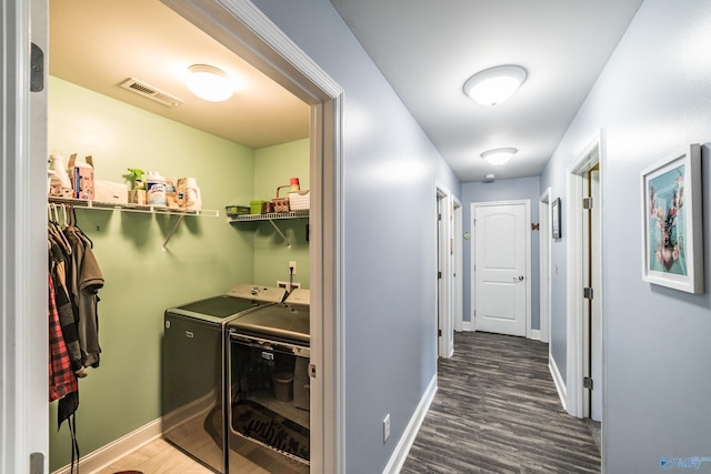 clothes washing area with laundry area, washer and clothes dryer, baseboards, and wood finished floors