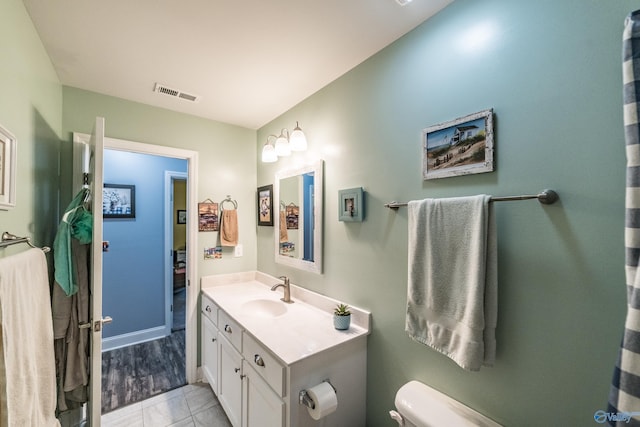 bathroom with vanity, baseboards, toilet, and visible vents