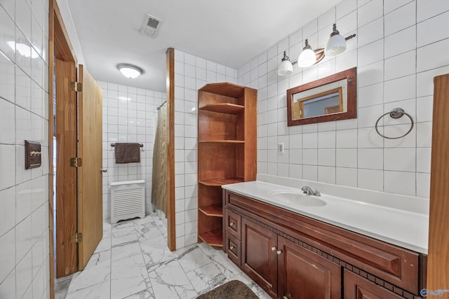 full bathroom with visible vents, marble finish floor, vanity, and tile walls