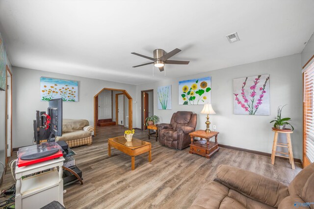 living room with baseboards, wood finished floors, visible vents, and a ceiling fan