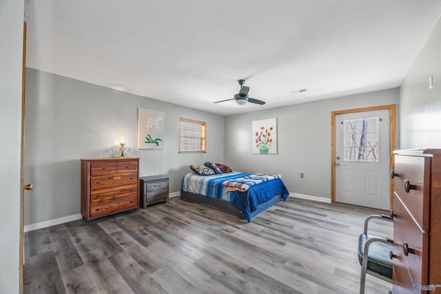 bedroom featuring a ceiling fan, visible vents, baseboards, and wood finished floors