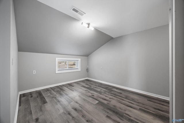 bonus room featuring baseboards, visible vents, vaulted ceiling, and wood finished floors