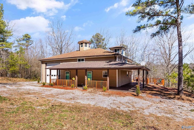 rear view of house with covered porch and roof with shingles