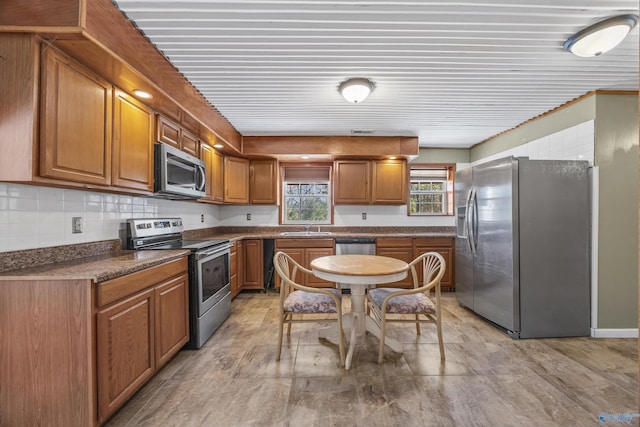 kitchen with dark countertops, brown cabinetry, stainless steel appliances, and a sink