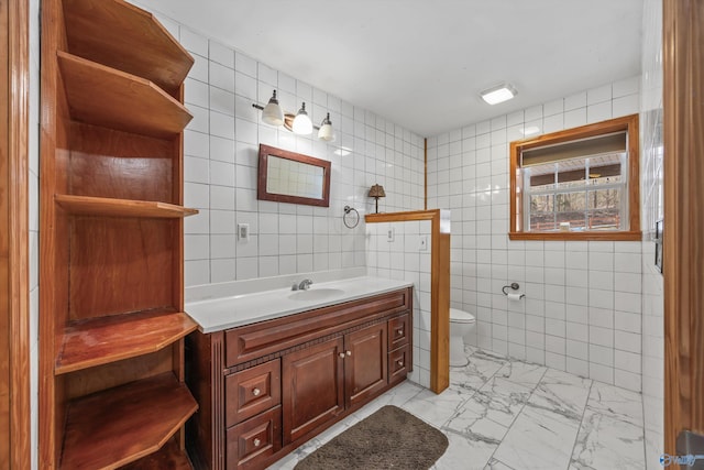 full bathroom with toilet, marble finish floor, vanity, and tile walls