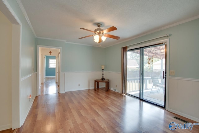 spare room with light wood-type flooring, ornamental molding, and a textured ceiling