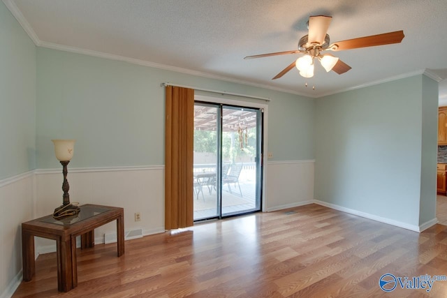 unfurnished room featuring light wood-style floors, visible vents, ornamental molding, and a ceiling fan