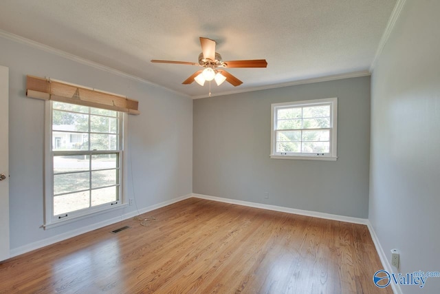 spare room with light wood finished floors, plenty of natural light, visible vents, and baseboards