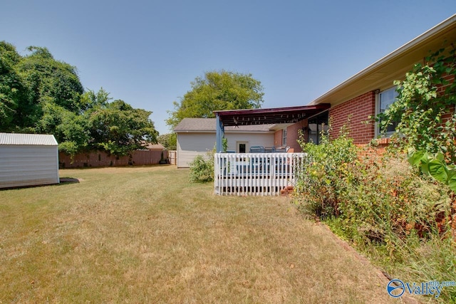 view of yard featuring a shed, an outdoor structure, and fence