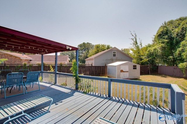 wooden terrace featuring a storage shed, a fenced backyard, an outbuilding, a yard, and outdoor dining space