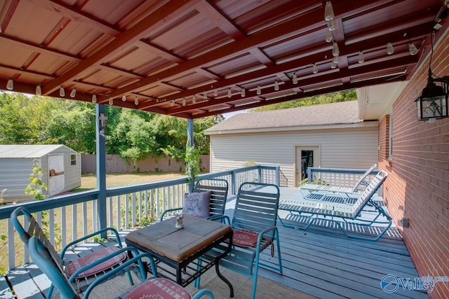 deck with a shed, fence, outdoor dining area, and an outbuilding