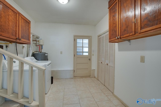 clothes washing area featuring cabinet space, water heater, washer / clothes dryer, and light tile patterned flooring